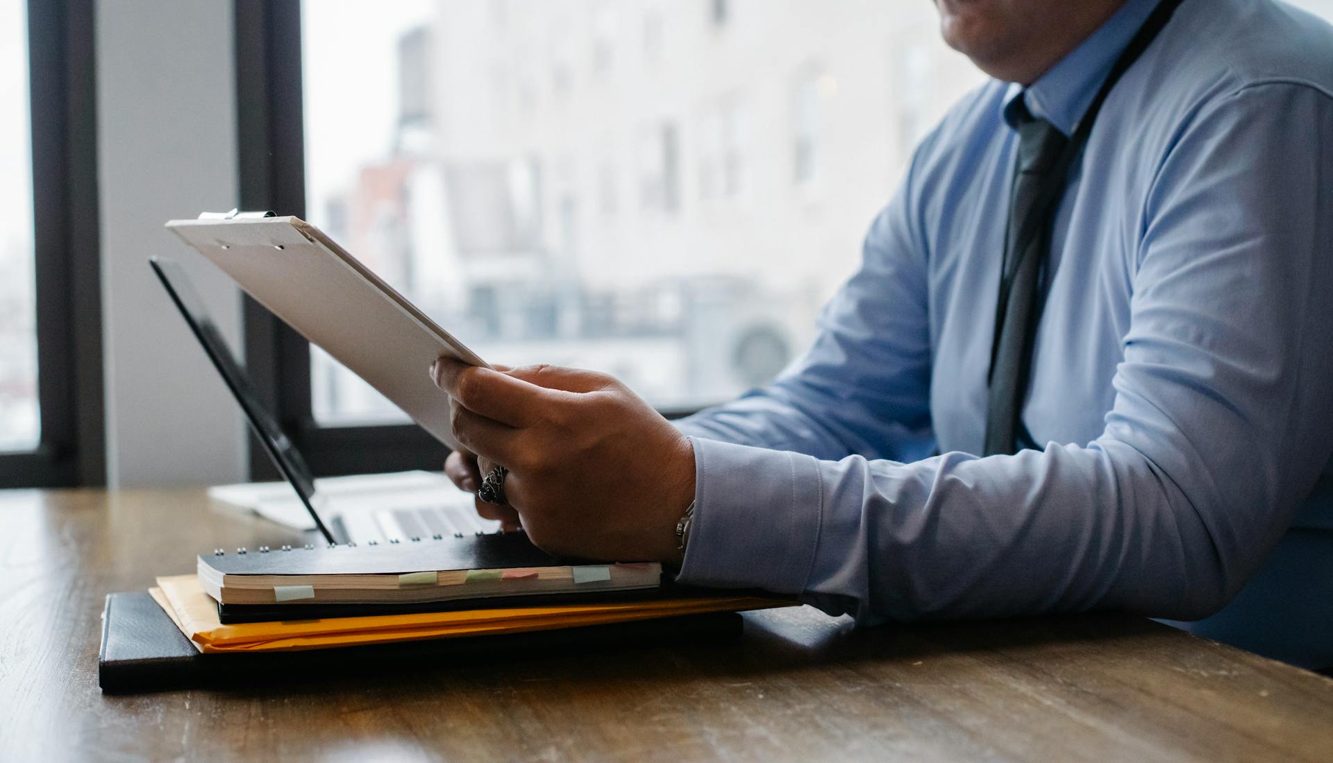 Crop businessman reading documents on clipboard in office