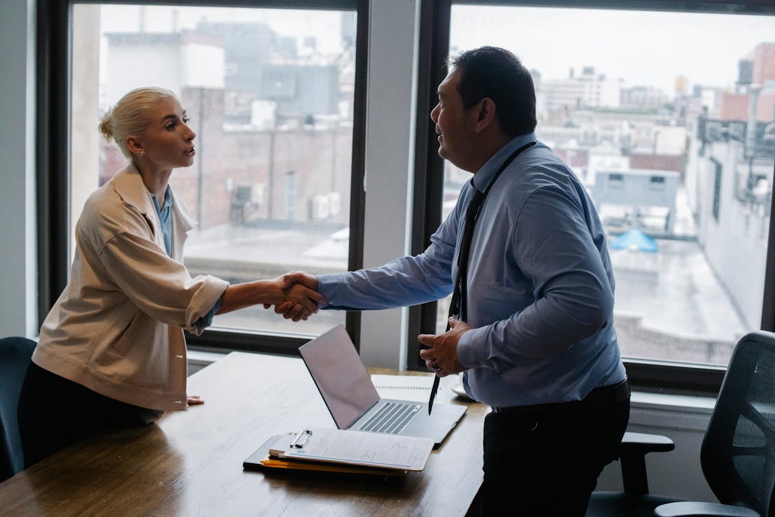 Free Young woman shaking hands with boss after business presentation Stock Photo