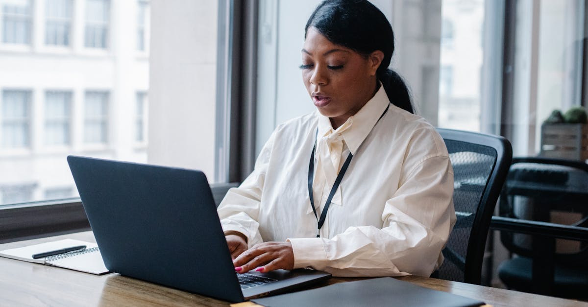 A person with focused expression typing on a sleek laptop, a cup of coffee nearby