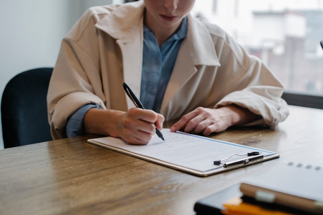 Free Focused woman writing in clipboard while hiring candidate Stock Photo