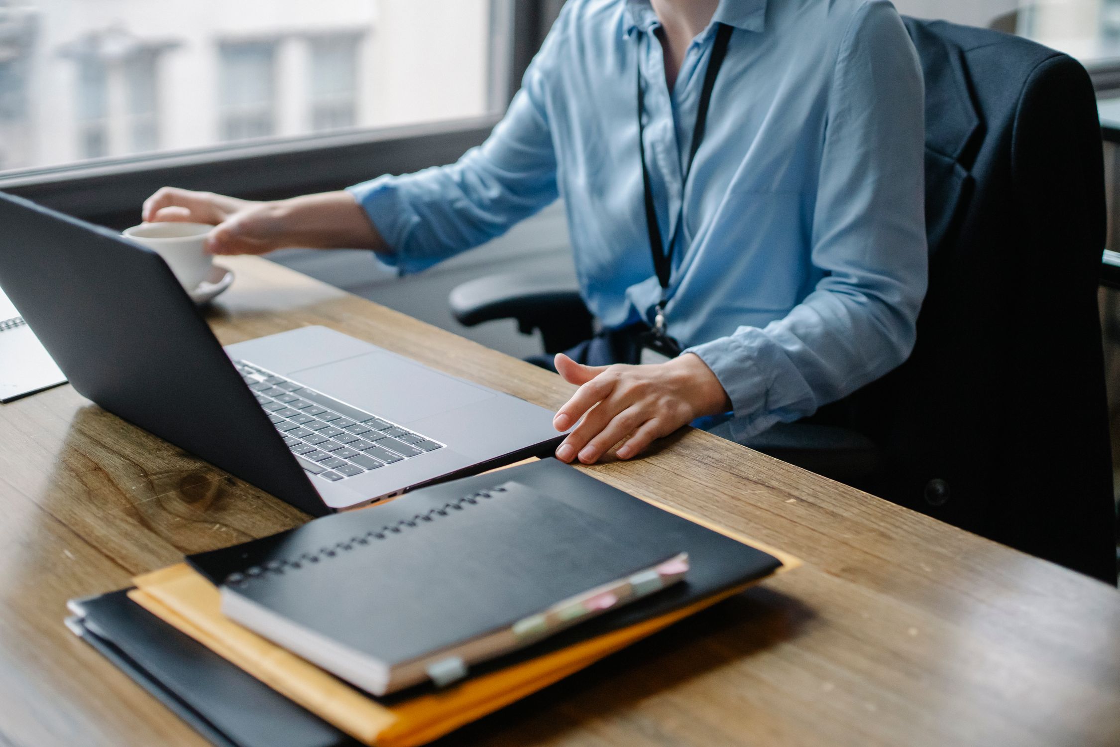 Woman working at desk with laptop and cup of coffee in an office environment