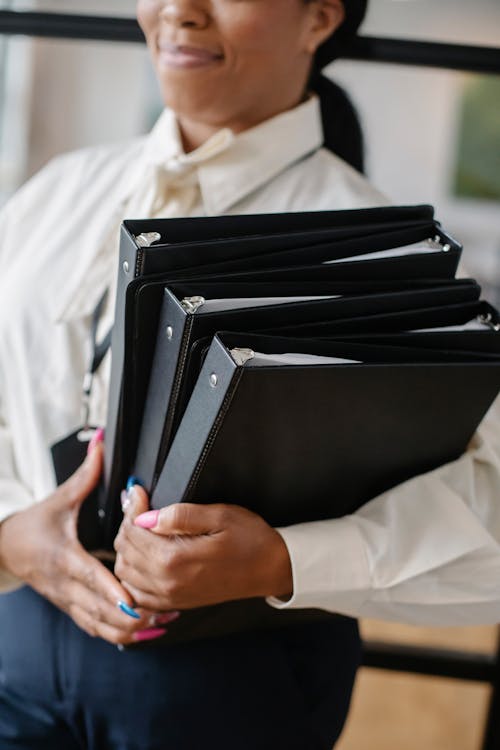 Black woman carrying pile of documents in office