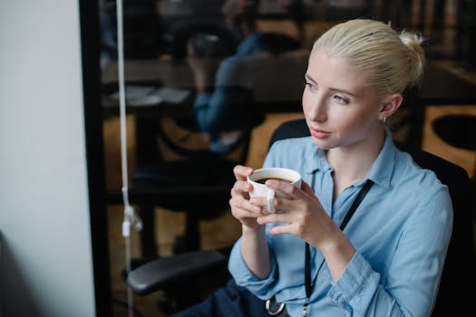 From above of female worker wearing formal clothes having cup of hot coffee in office