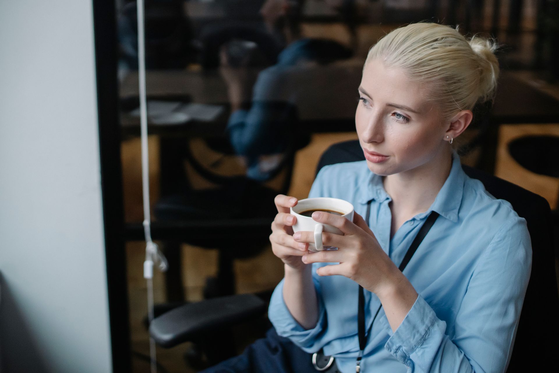 From above of female worker wearing formal clothes having cup of hot coffee in office