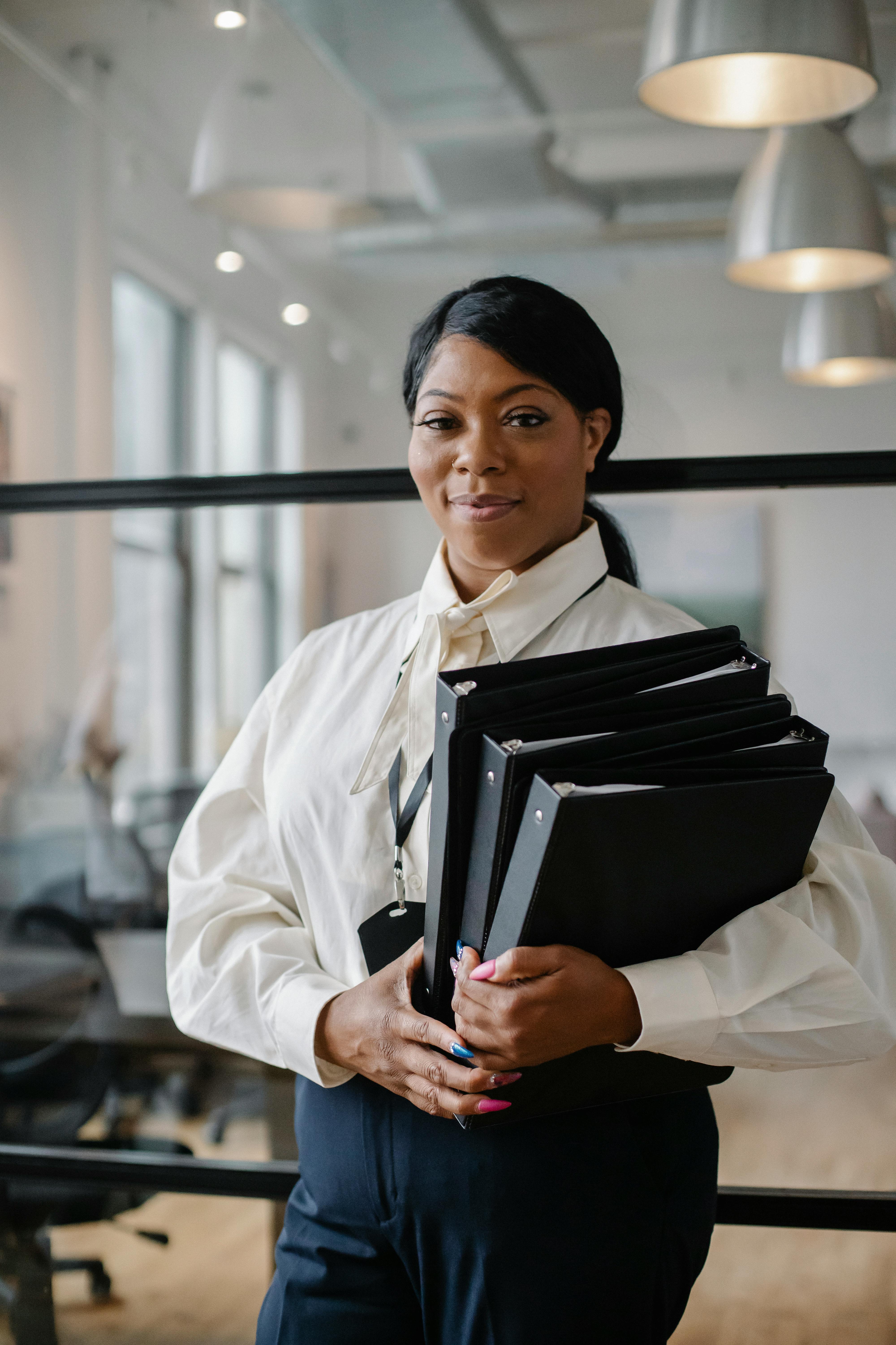 positive black woman carrying documents in folders