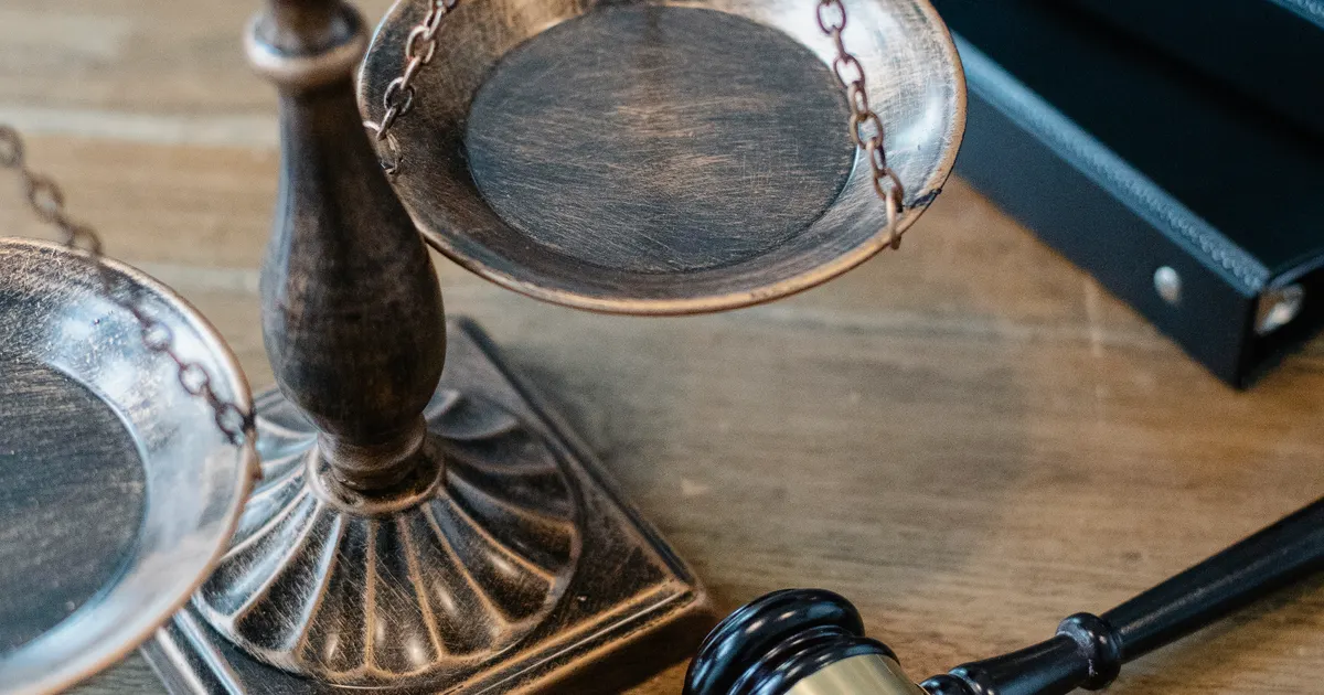 Antique brass scales and a gavel on a wooden desk, representing enterprise AI supply chain due diligence