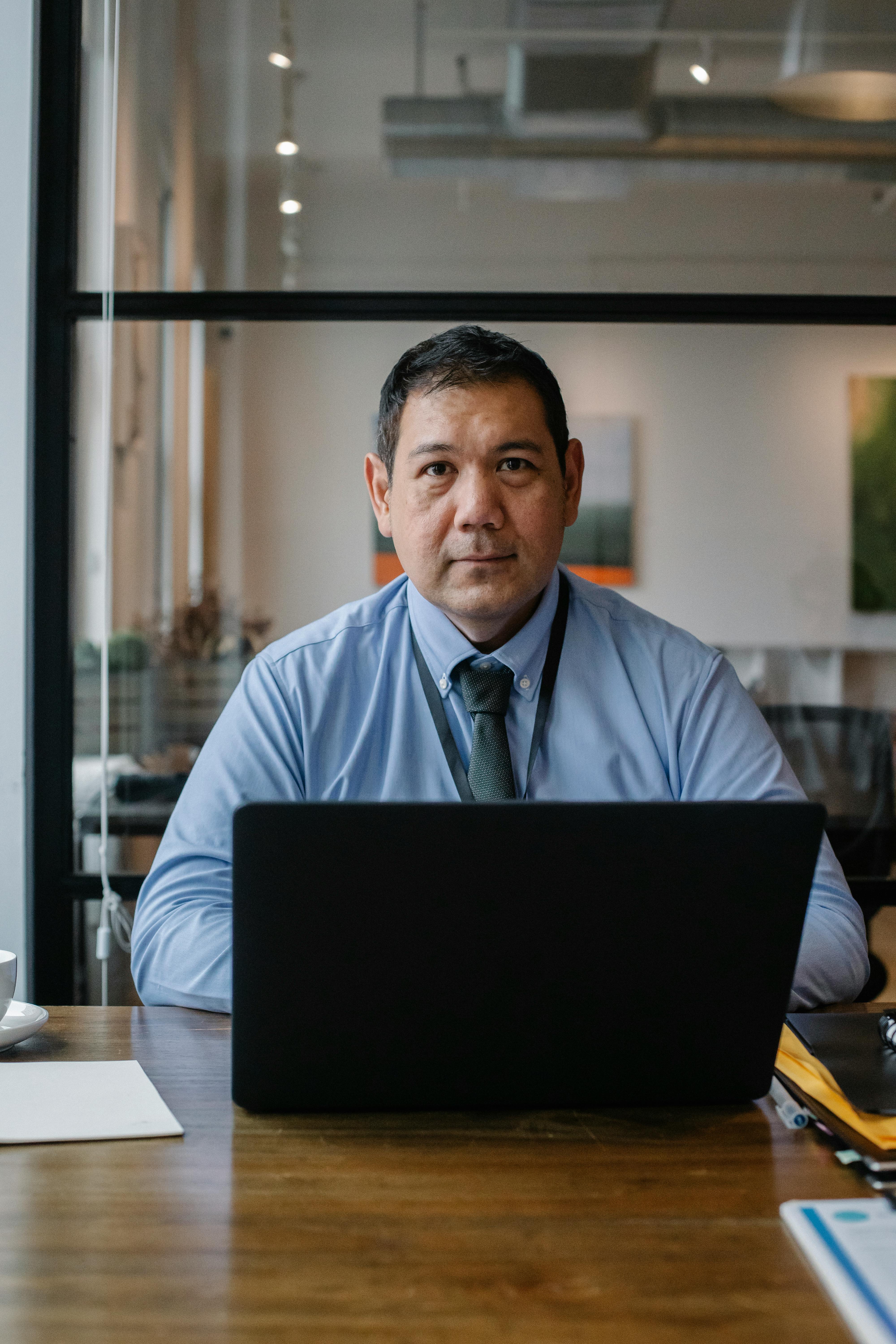 serious ethnic male executive employee working at laptop