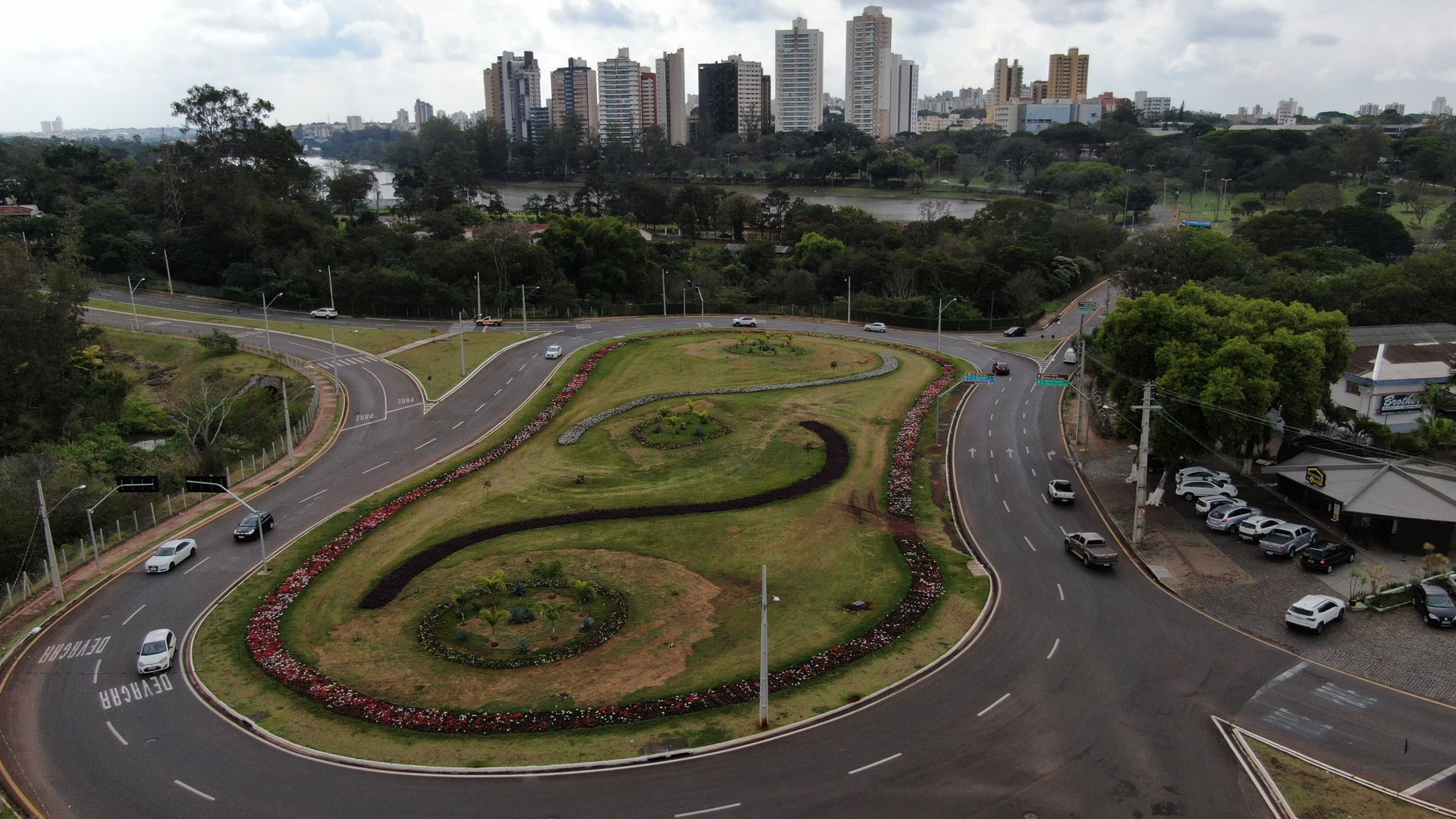 Aerial view of urban roundabout in Igapó, Brazil with green surroundings and city skyline.