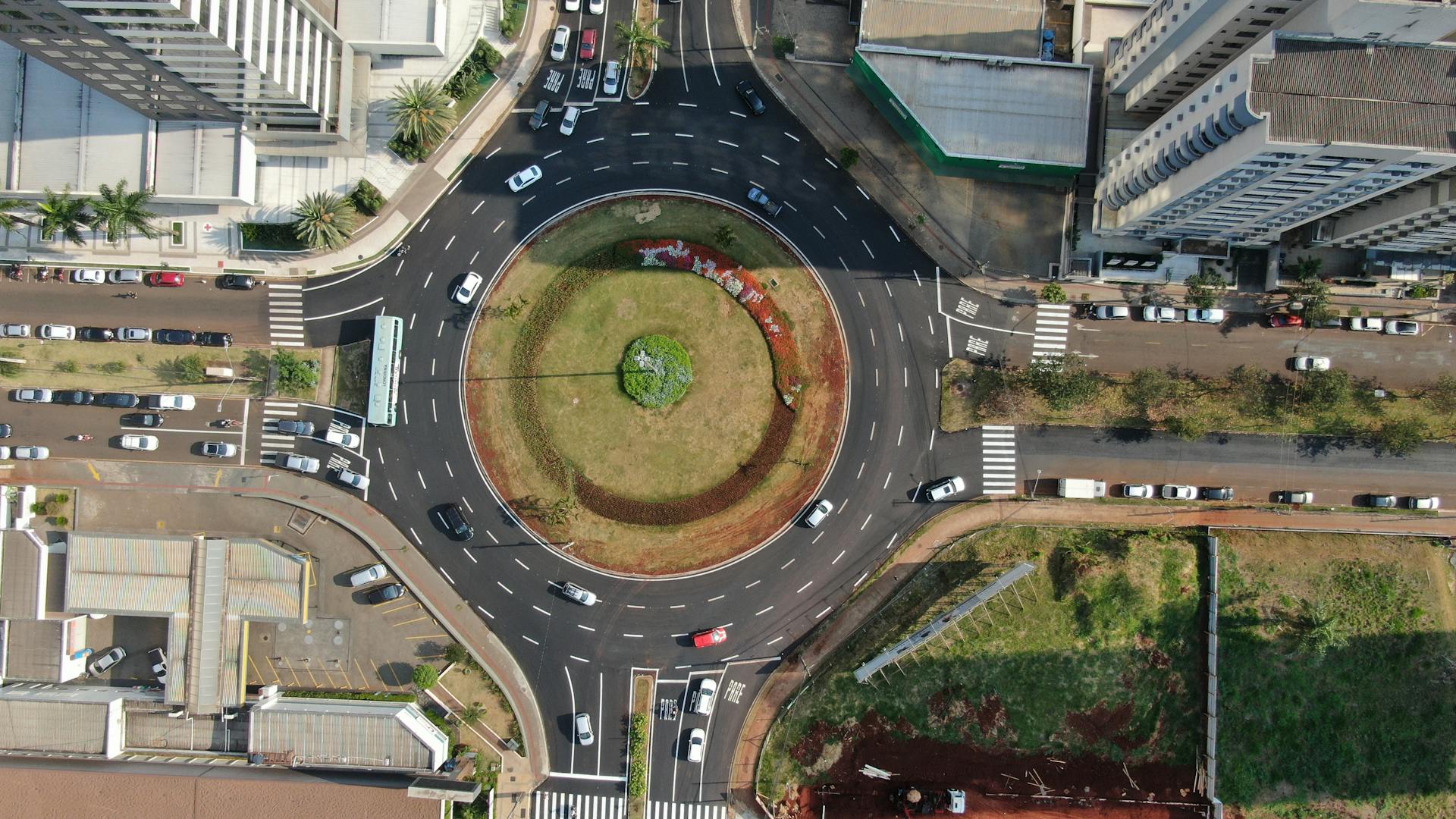 Aerial view of a roundabout surrounded by buildings and green spaces in Gleba Fazenda Palhano, Brazil.