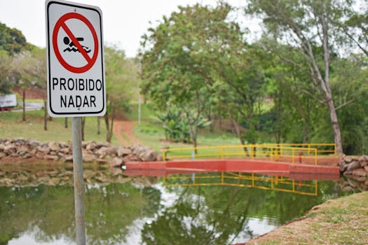 Proibido Nadar sign by a reflective pond in a lush park setting emphasizing safety.