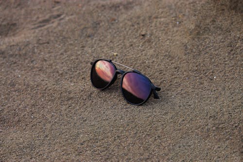 Close-Up Shot of Black Sunglasses on the Sand