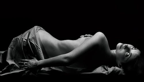 Grayscale Photo of a Naked Woman Lying Down