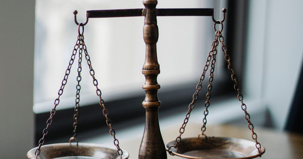 A scale of justice and a gavel on a wooden desk in an office.