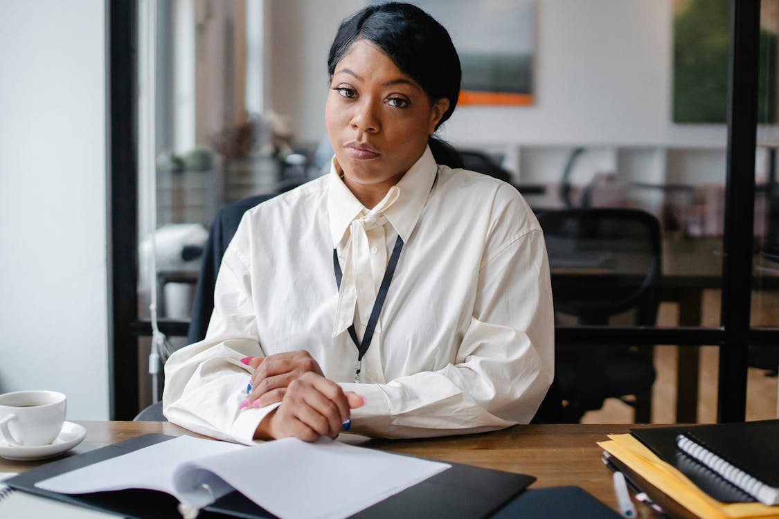 Free Serious black businesswoman sitting at desk in office Stock Photo