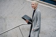 一位自信的年轻女实业家手持文件走在城市街道上，散发着积极的风格