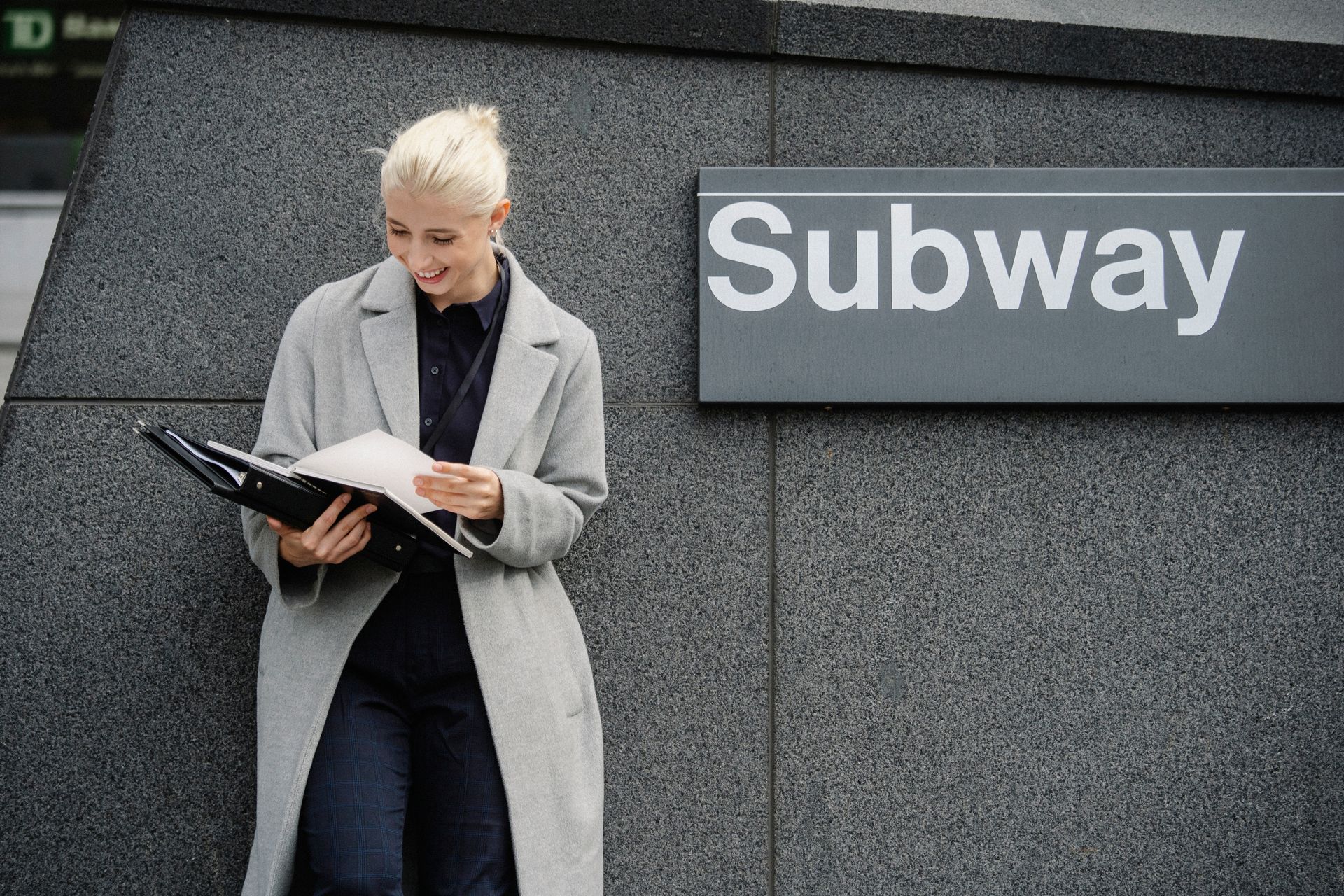 Happy businesswoman reading documents near subway station