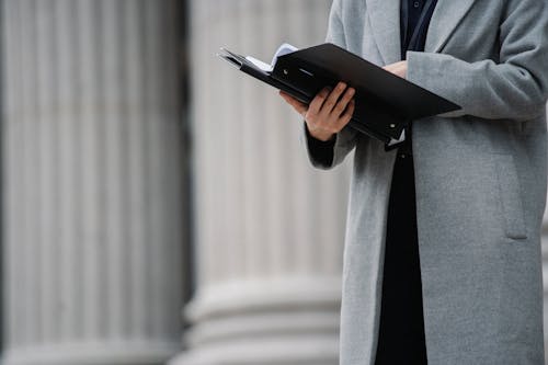 Crop faceless businesswoman reading papers on street