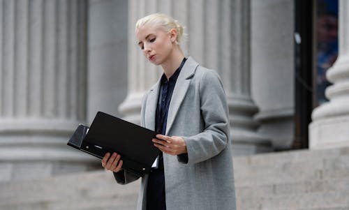 Kontemplacyjna Bizneswoman Czyta Dokumenty W Folderze Na Zewnątrz Budynku