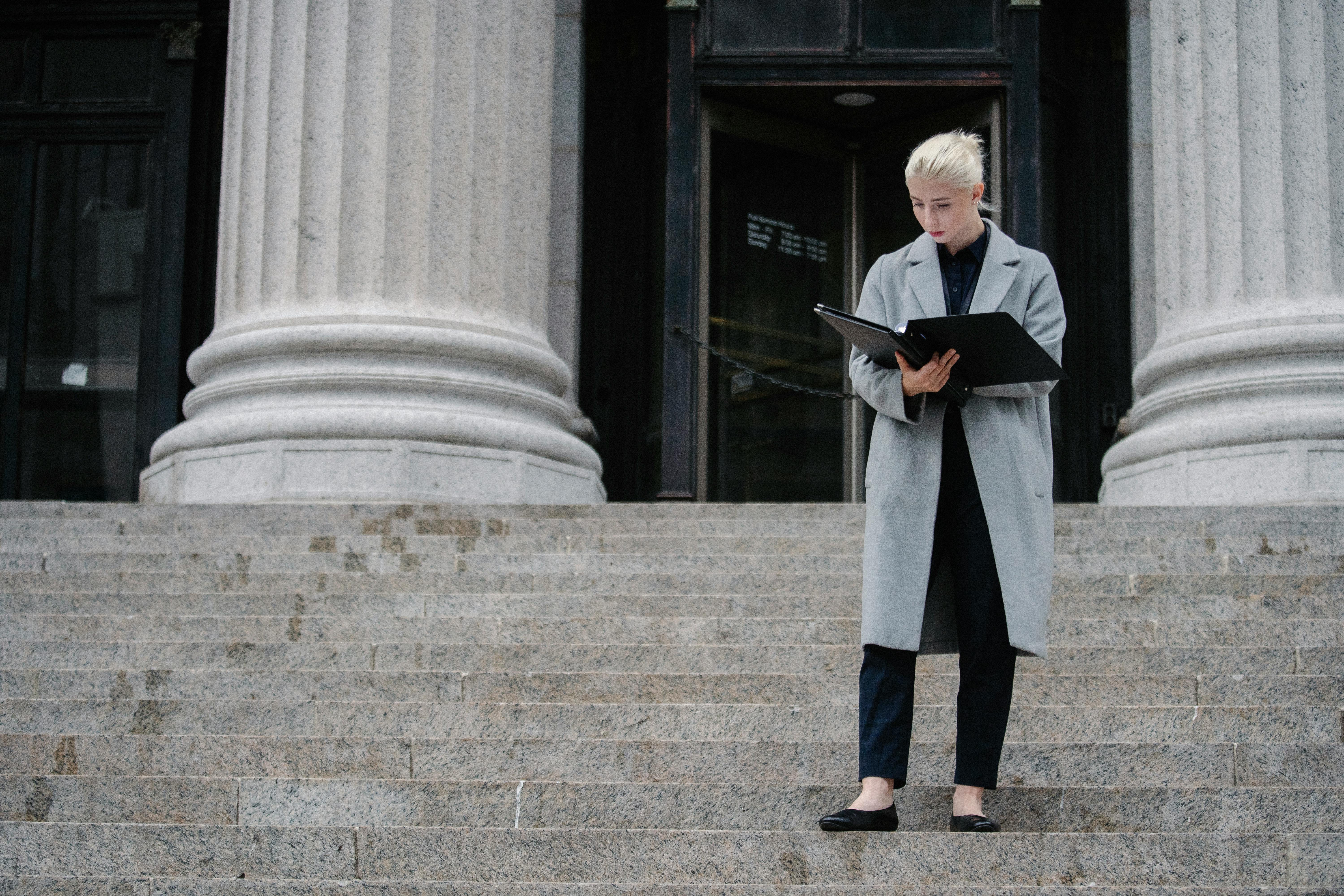 serious businesswoman reading report outside stone building