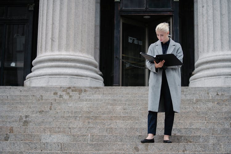 Serious Businesswoman Reading Report Outside Stone Building