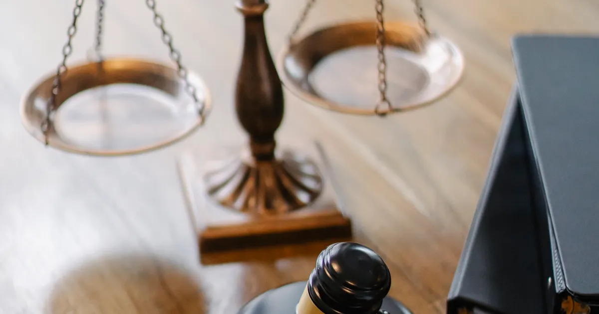 Brass scales and a gavel on a light wooden desk, representing the regulation and litigation covered this week