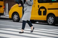 Side view crop female in formal clothes carrying documents folders crossing busy road in urban city district