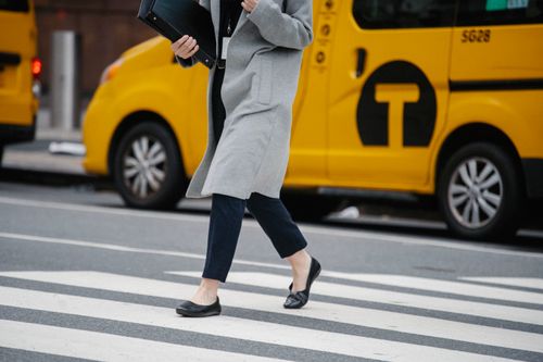 Free Side view crop female in formal clothes carrying documents folders crossing busy road in urban city district Stock Photo