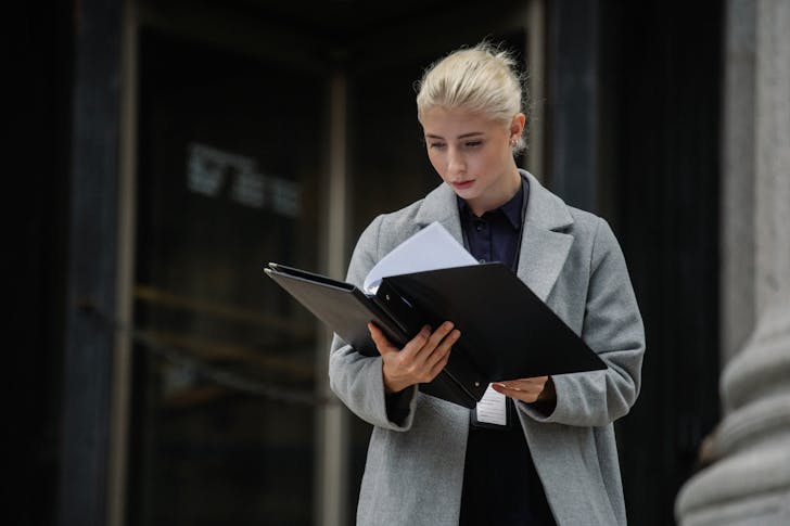 Concentrated businesswoman reading report outside office building