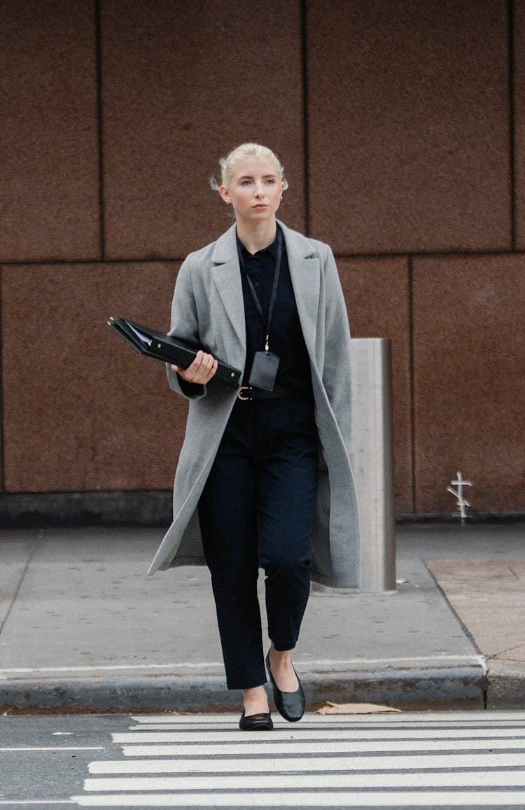 Serious Businesswoman With Folders Crossing Road