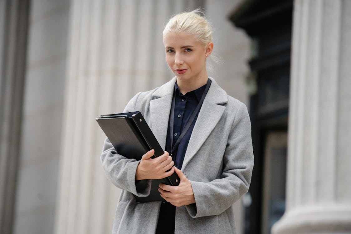 Free Confident businesswoman with folders standing outside stone building Stock Photo