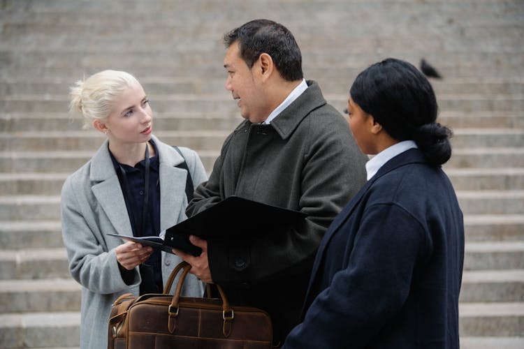 Serious Diverse Colleagues Discussing Project Outside Stone Building