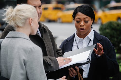 Multiethnic coworkers examining documents on city street