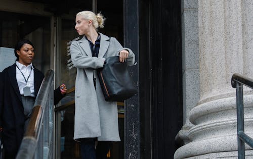 Free Low angle of happy young multiracial female colleagues in elegant clothes standing near office building with columns after workday Stock Photo