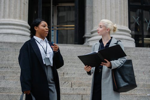 Élégantes Partenaires D'affaires Féminines Diverses Avec Des Documents Parlant Dans La Rue