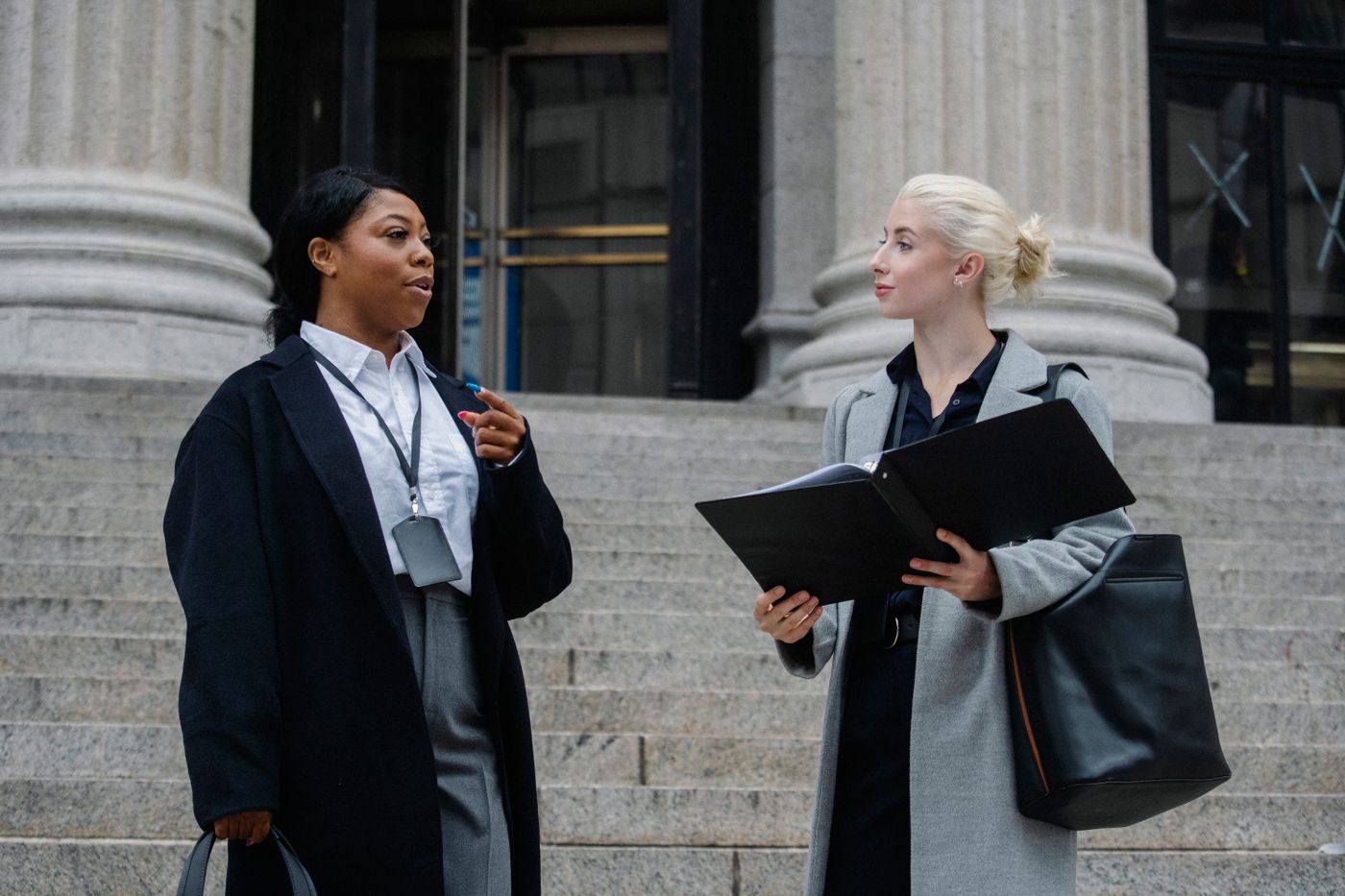 Two professionals discussing records outside a courthouse