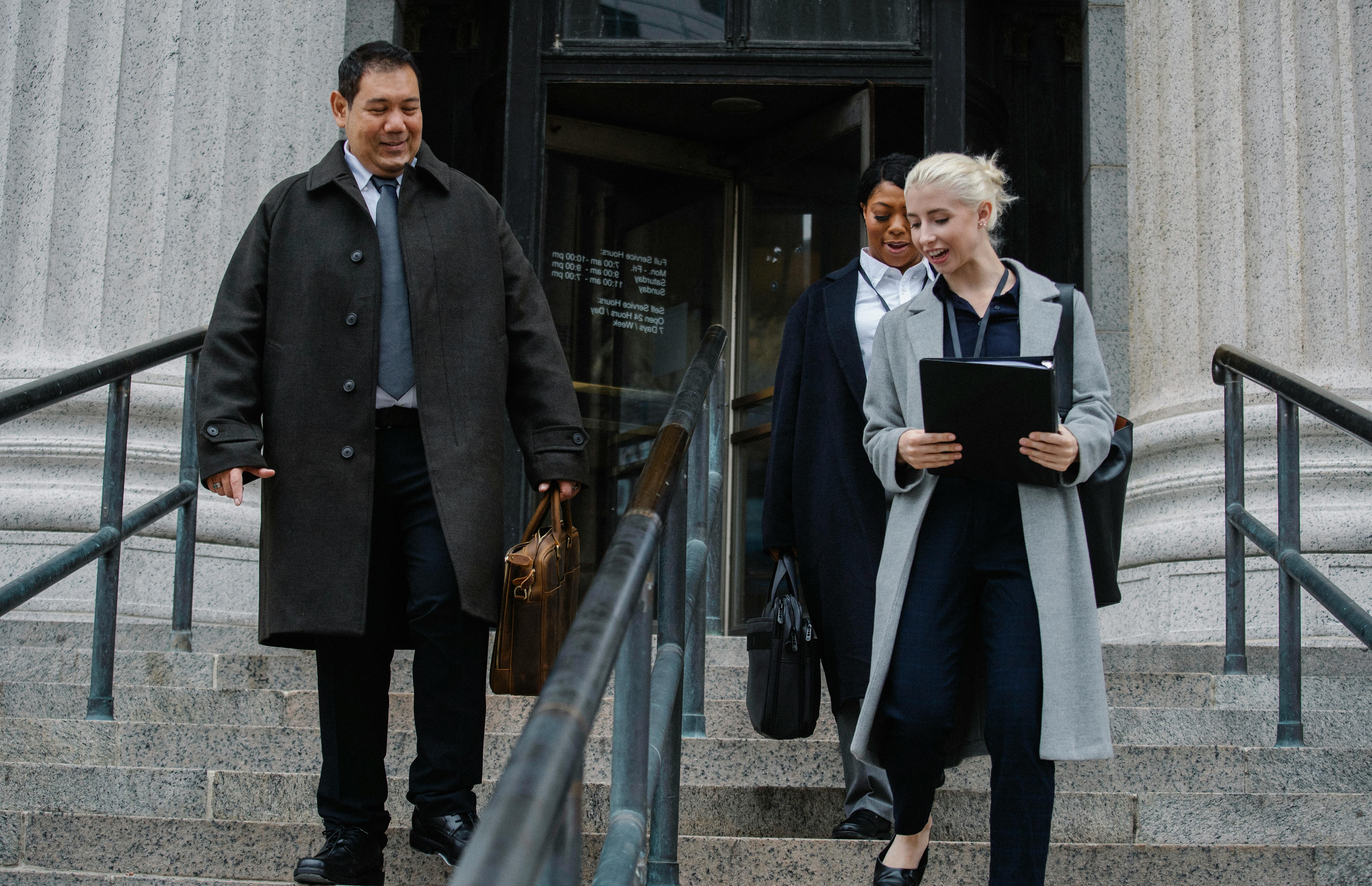 smiling diverse coworkers walking downstairs and chatting after successful meeting