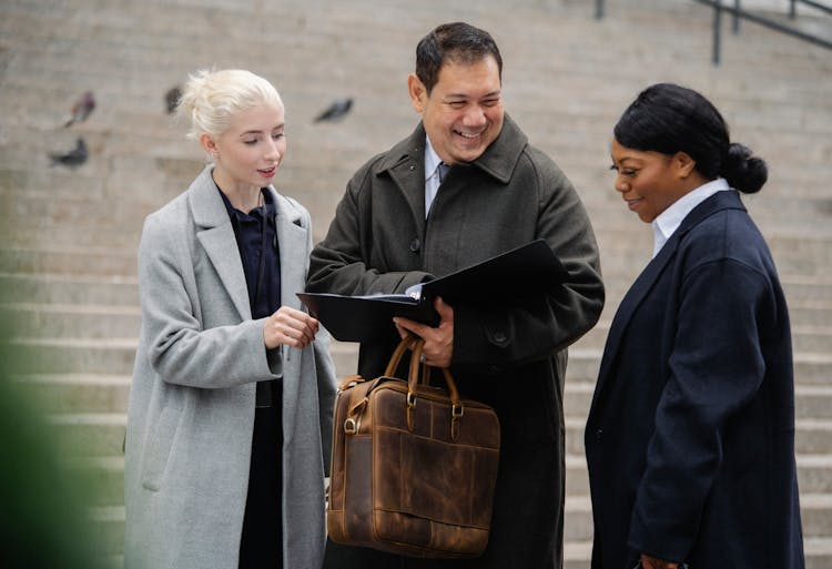 Happy Multiethnic Coworkers Discussing Documents On City Street