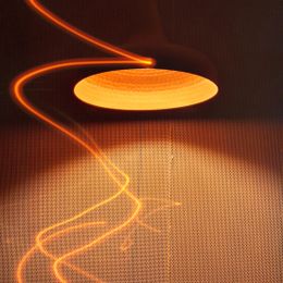 Warm amber pendant lamp glowing with trails of light — photo by Niju George on Pexels