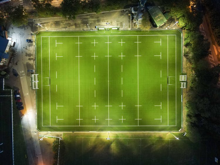 Illuminated Empty Green Rugby Stadium In Evening