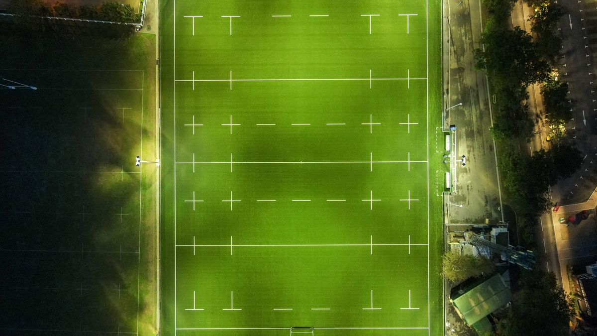 Aerial view of a floodlit rugby pitch at dusk, the kind of match day that brings fans to accommodation near Kingsholm Stadium