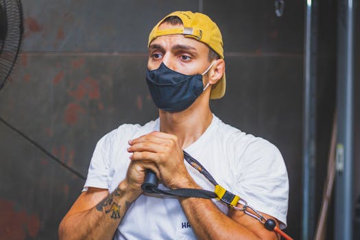 A masked man concentrating on his workout with resistance bands in an indoor gym setting.