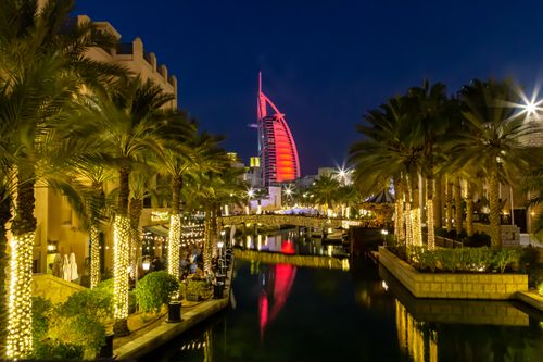 Free Captivating nighttime view of the Burj Al Arab with illuminated palm trees and canal in Dubai. Stock Photo