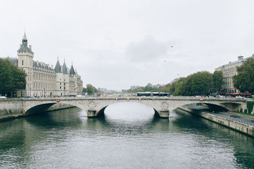 Free Scenic view of a historic bridge over the serene river with classic Parisian architecture in the background. Stock Photo