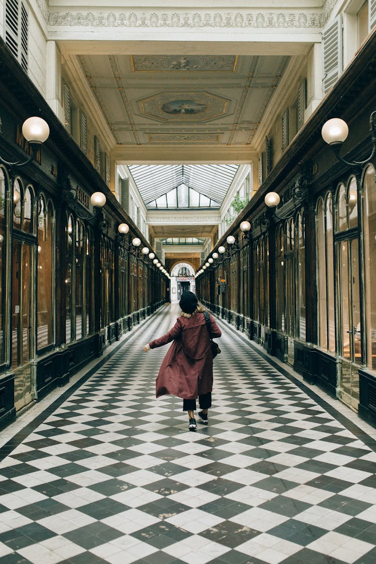 Woman In Maroon Coat Walking In A Hallway