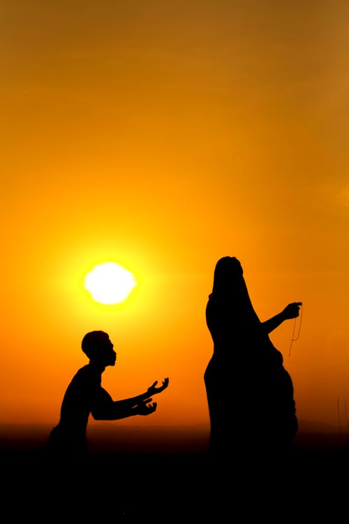 Pleading man and arrogant woman against sundown sky