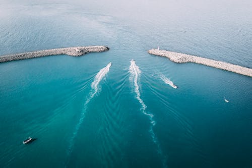 Ships sailing through sea and leaving ships wakes between breakwaters