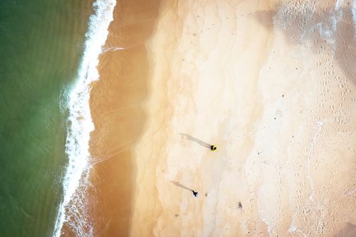 Free Drone view of green wavy reservoir and travelers on sandy shore covered with footprints Stock Photo