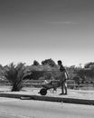 Black and White Photo of a Man Pushing a Wheelbarrow