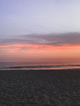 A tranquil scene of a beach at sunset with a pink sky over the ocean horizon, perfect for relaxation themes.
