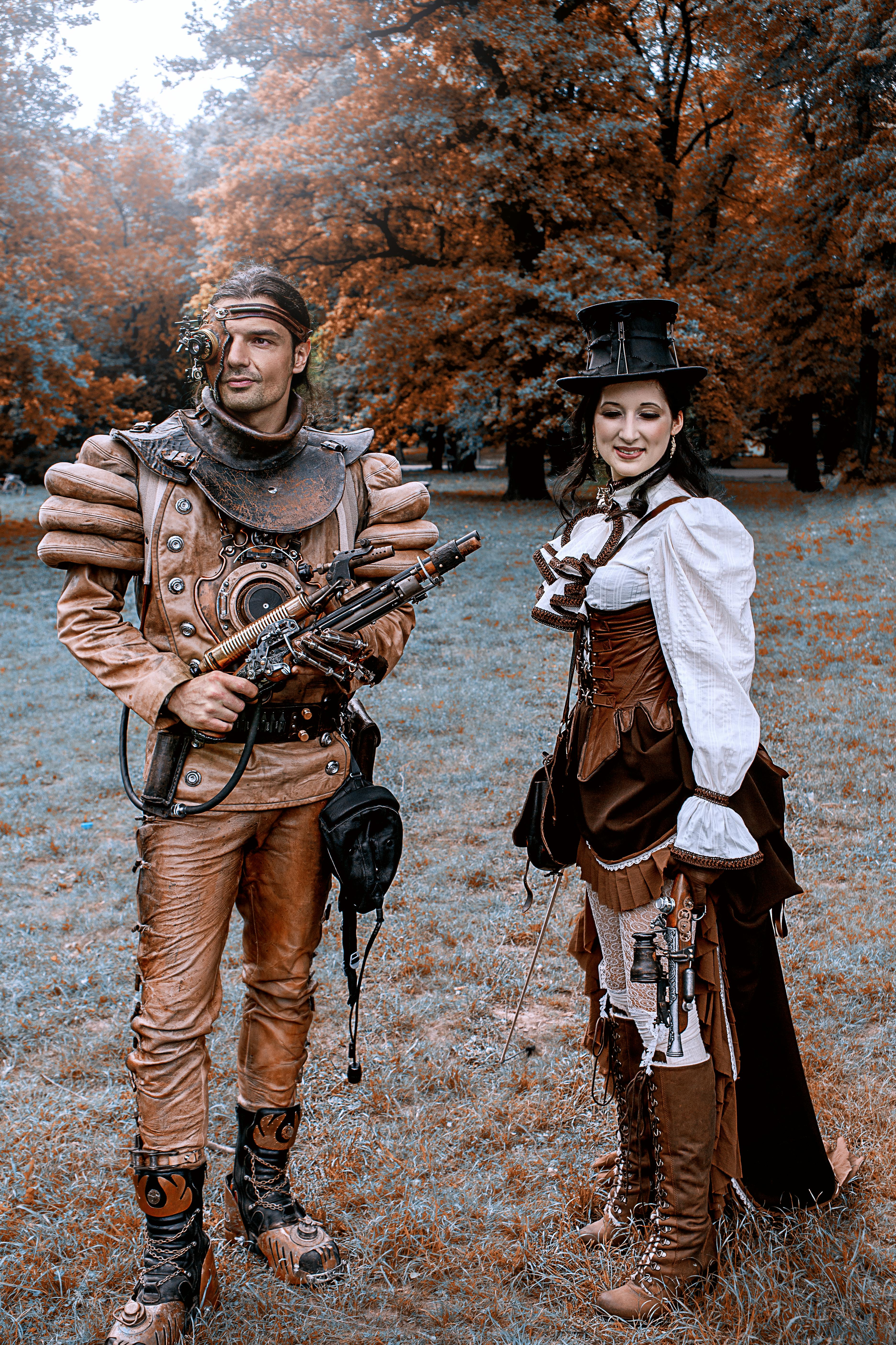 A steampunk couple in elaborate costumes poses in an autumn park setting in Leipzig.